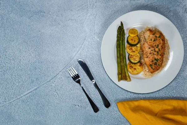 Kahverengi pirinç yatağında pişmiş tavuk göğsü. Yanında da kabak ve kuşkonmaz.. 