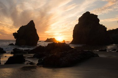 Malibu, California 'da kayaların siluetlerine karşı güzel, turuncu bir gün batımı.