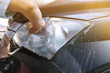 Benzin istasyonunda güç tamponu makinesiyle arabada büyük bir far temizliği, önce ve sonra güç tampon makinesi kullanarak arabanın farlarını temizleyen bir tamirci ile araba konsepti. 