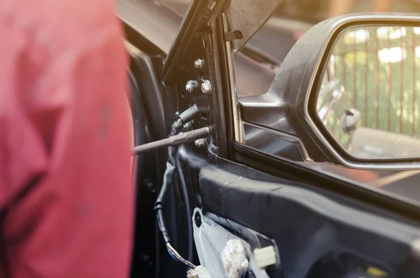 Otomobil tamirhanesinde arabanın motorunu tamir ediyorum. Üniformalı tamirciler otomobil servisinde çalışırken araba tamir ediyorlar