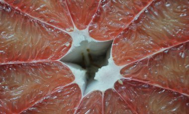 Kırmızı arkaplandaki kırmızı çiçek yapraklarının yüzeyi, kırmızı pomelo, yarı yarıya kesilmiş, pomelo eti dokusu.