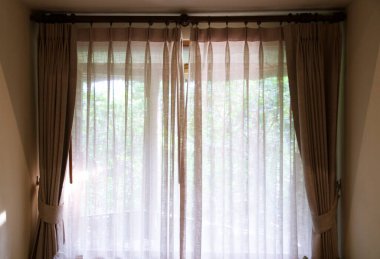 Yatak odasından terasa ya da balkona bak. Güneş gün batımında şeffaf bir perde ve ağaçların arasından parlıyor. .