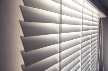 Kapalı beyaz renkli tahta panjurlar. Şehirdeki pencerelerden geçen güneş ışığı. Seçmeli odak ve ışık arkaplanı.