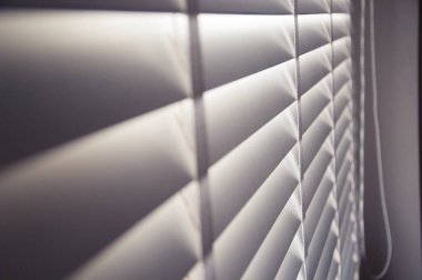 Kapalı beyaz renkli tahta panjurlar. Şehirdeki pencerelerden geçen güneş ışığı. Seçmeli odak ve ışık arkaplanı.