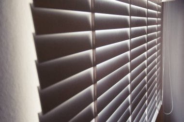 Kapalı beyaz renkli tahta panjurlar. Şehirdeki pencerelerden geçen güneş ışığı. Seçmeli odak ve ışık arkaplanı.