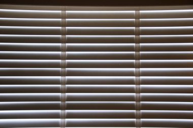 Kapalı beyaz renkli tahta panjurlar. Şehirdeki pencerelerden geçen güneş ışığı. Seçmeli odak ve ışık arkaplanı.