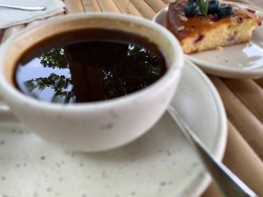 Çikolata soslu kek ve ahşap bir masada bir fincan sade kahve. Lezzetli atıştırmalıklar ya da bir dilim kek ile kahve zamanı.