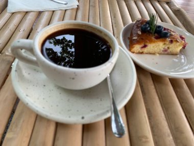 Çikolata soslu kek ve ahşap bir masada bir fincan sade kahve. Lezzetli atıştırmalıklar ya da bir dilim kek ile kahve zamanı.