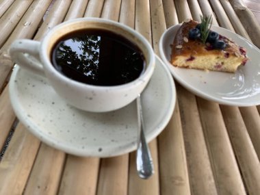 Çikolata soslu kek ve ahşap bir masada bir fincan sade kahve. Lezzetli atıştırmalıklar ya da bir dilim kek ile kahve zamanı.