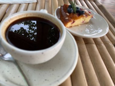 Çikolata soslu kek ve ahşap bir masada bir fincan sade kahve. Lezzetli atıştırmalıklar ya da bir dilim kek ile kahve zamanı.