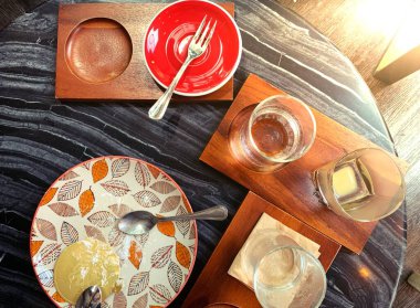 İçinde fırın keki kalıntıları olan kirli bir tabak, kirli çatal bıçak takımı ve mermer bir masanın üzerinde bir kupa kahve. Kullanılmış tabaklar yemeğin, yemeğin, kirli tabağın ve tatlının sonunu simgeler.