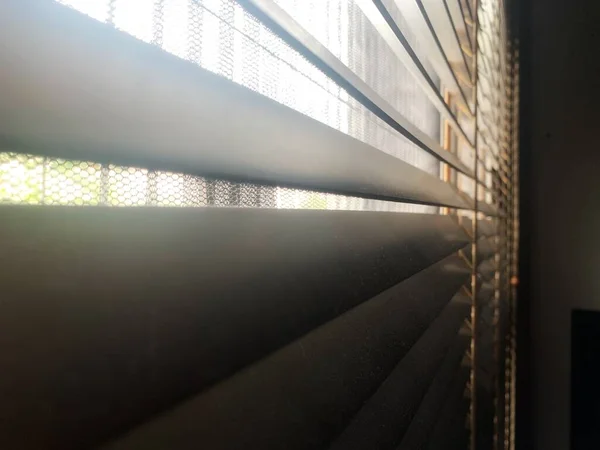 Hava kirliliği krizi, Venedik panjurlarındaki ya da gri tahta panjurlardaki tozu oluşturur. Güneş ışığı ahşap panjurların arasından parlıyor toz lekeleri kirli pencere perdeleri yakın çekim tahtaları yatay.. 