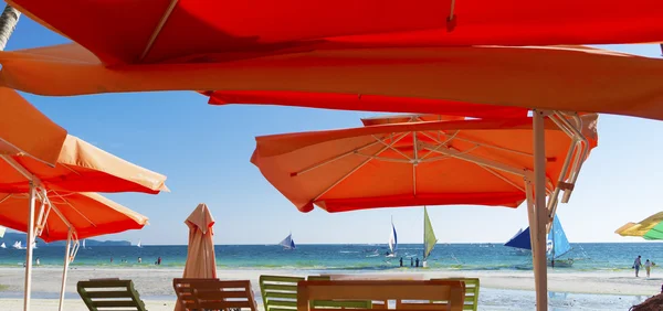 Orange umbrellas on tropical beach — Stock Photo, Image