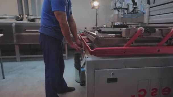 Hombre blanco trabajando. El proceso de fabricación de papel pintado, la aplicación de pintura a una muestra. Fondos de pantalla Producción. Fábrica moderna — Vídeos de Stock