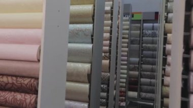 Yeni örneklerle ayakta duruyor. Duvar kağıdıyla yuvarlanıyor. Duvar kağıdı örnekleriyle birlikte dükkanda duruyor. Desenli duvar kağıdı