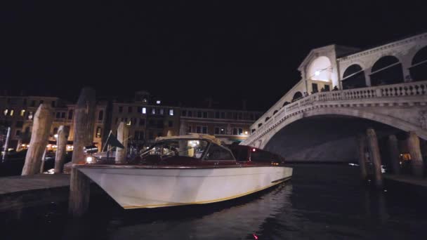 Motorboot afgemeerd bij de Rialtobrug, nachtschot. Grand Canal 's nachts — Stockvideo