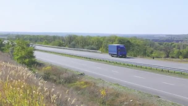 Ciężarówka jedzie autostradą. Ciężarówka jeździ po autostradzie wokół pól i drzew — Wideo stockowe