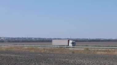 Bir kamyon şehir dışında bir yolda ilerliyor, modern bir kargo kamyonu otoyolda gidiyor.