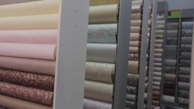 Duvar kağıdı örnekleriyle birlikte dükkanda duruyor. Yeni örneklerle ayakta duruyor. Duvar kağıdıyla yuvarlanıyor. Desenli duvar kağıdı