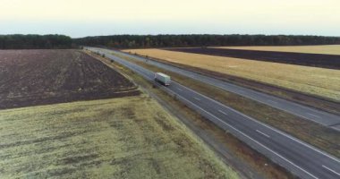 Kamyon yolda gidiyor, tarlalar arka planda. Kamyon, tarımsal alanların ortasında yol boyunca gidiyor..