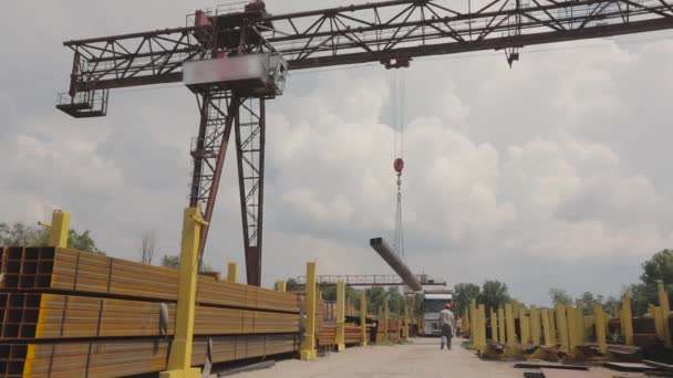 Una grúa pórtico carga metal en un camión, carga metal en un almacén, una grúa pórtico grande, la gente trabaja en un almacén de metal — Vídeos de Stock