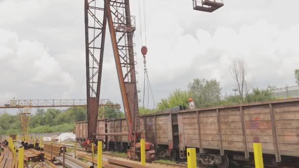 Déchargement du tuyau profilé par une grue à portique d'un wagon de marchandises, charge du métal dans un entrepôt, une grande grue à portique — Video