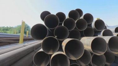 Geniş çaplı metal borulardan bak. Metal bir depoda büyük çaplı metal borular, açık hava deposunda büyük borular, sıra sıra yığılmış büyük çaplı borular.