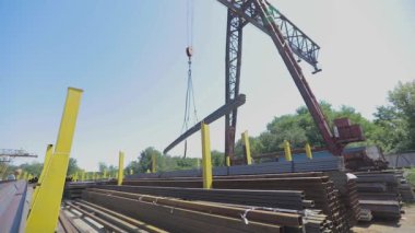 Bir vinç yardımıyla metal yükleme, bir depoda çalışma, açık havada metal deposu, metal ürünlerin taşınması.