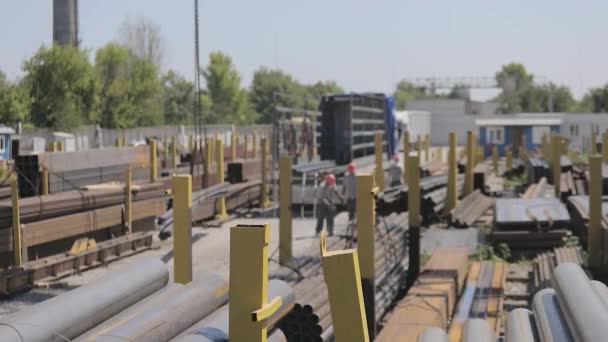 Рабочий процесс на складе с металлом. Рабочие разгружают металл в грузовике, стоящем под краном, рабочие на рампе. Погрузка грузовика с портальным краном — стоковое видео