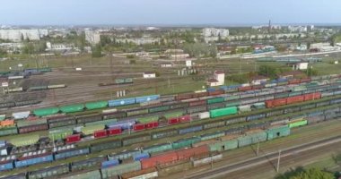 Demiryolu kavşağında bir sürü demiryolu manzarası var. Renkli trenler büyük bir tren istasyonunda duruyor.