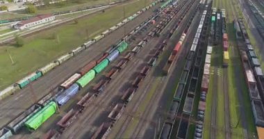 Demiryolu kavşağındaki yük trenlerinin en üst görüntüsü. Yük trenleri ile büyük tren kavşağı manzaralı. İstasyondaki trenlerin üzerinden uçuyor.