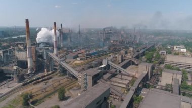 Bitkinin bacasından çıkan kalın beyaz duman. Büyük bir fabrikadan salınımlar. Fabrikanın dumanı tüten bacasının yanında uçuyor.