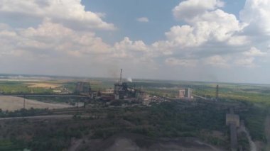 Bitkinin bacasından çıkan kalın beyaz duman. Büyük bir fabrikadan salınımlar. Fabrikanın dumanı tüten bacasının yanında uçuyor.