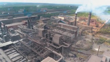 Bitkinin bacasından çıkan kalın beyaz duman. Büyük bir fabrikadan salınımlar. Fabrikanın dumanı tüten bacasının yanında uçuyor.