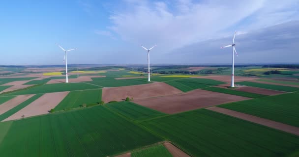 Tarım alanlarından ve rüzgar jeneratörlerinden oluşan hava panoramaları elektrik üretiyor. Alternatif enerji, yeşil alanda üç rüzgar türbini. — Stok video