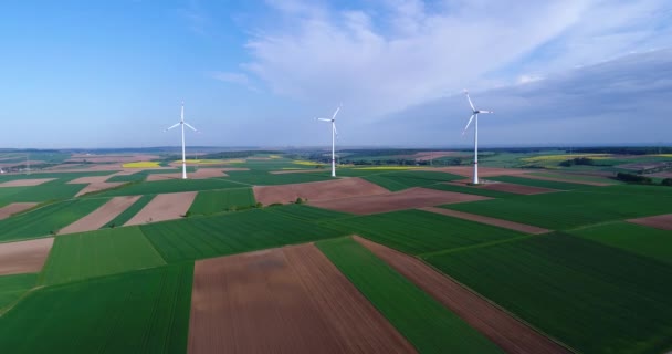 Panoramas de ar de campos agrícolas e geradores eólicos produzindo eletricidade. Energia alternativa, três turbinas eólicas em um campo verde — Vídeo de Stock