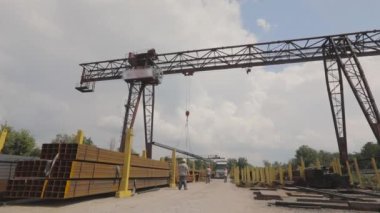 Bir vinç bir kamyona metal yükler, bir depoya metal yükler, büyük bir vinç, insanlar metal bir depoda çalışır.