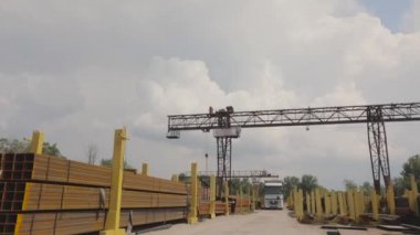 Bir vinç bir kamyona metal yükler, bir depoya metal yükler, büyük bir vinç, insanlar metal bir depoda çalışır.