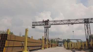 Bir vinç bir kamyona metal yükler, bir depoya metal yükler, büyük bir vinç, insanlar metal bir depoda çalışır.