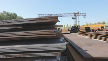 Açık gökyüzünün altındaki metal bir skala üzerindeki metal levhalar, iyi hava, arka planda kanatlı vinç olan metal levhalar, metal ürünler deposu, metal ürünler.