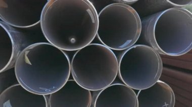 Geniş çaplı metal borulardan bak. Metal bir depoda büyük çaplı metal borular, açık hava deposunda büyük borular, sıra sıra yığılmış büyük çaplı borular.