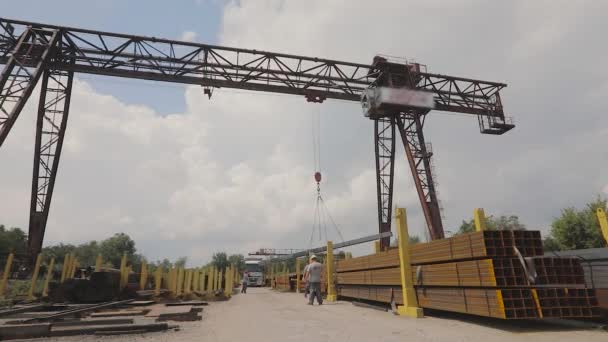 A gantry crane loads metal into a truck, loads metal in a warehouse, a large gantry crane, people work in a metal warehouse — Stock Video