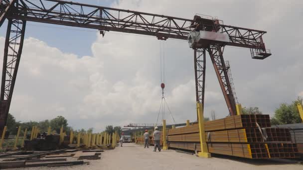 En portalkran lastar metall i en lastbil, lastar metall i ett lager, en stor portalkran, folk arbetar i ett metalllager — Stockvideo
