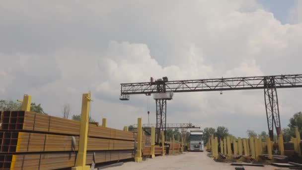 A gantry crane loads metal into a truck, loads metal in a warehouse, a large gantry crane, people work in a metal warehouse — Stock Video