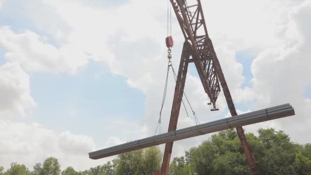 Déchargement du tuyau profilé par une grue à portique d'un wagon de marchandises, charge du métal dans un entrepôt, une grande grue à portique — Video