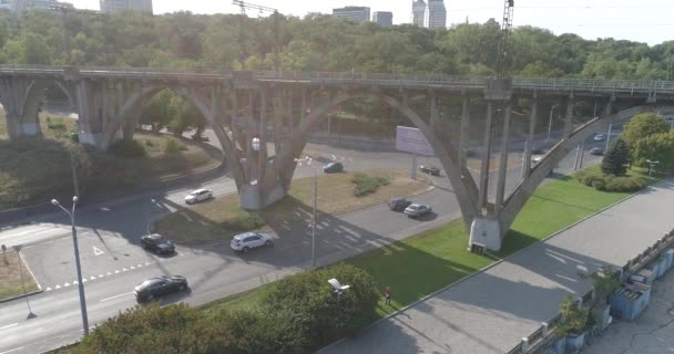 Tráfico de autos. Coches a lo largo de la carretera en la vista superior de la ciudad. Los coches pasan por debajo del puente. Muchos coches en la carretera que pasa por debajo de la vista superior del puente — Vídeos de Stock