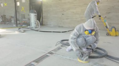 İnşaatçılar zemini özel ekipmanlarla cilalıyorlar. Beton yüzey öğütme. İnşaat alanında inşaatçılar