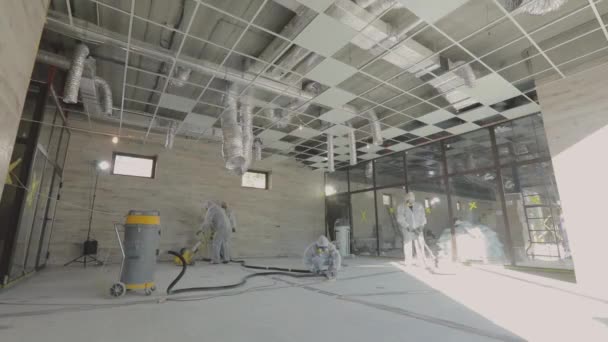 Working process at a construction site. Workers in protective suits are grinding the concrete floor. Construction professionals. Workers make concrete floor — Stock Video