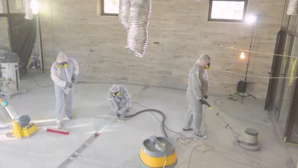 보호용 양복을 입은 근로자들 이 콘 크리 이트 바닥을 갈고 있다. 건설 현장에서의 작업 과정. 건축 전문가들. 노동자들 이 콘크리트 바닥을 만든다 — 비디오