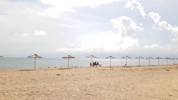 Strandparaplyer på en tom strand storm moln i bakgrunden. Blå moln långt ut i havet. Halmparaplyer på stranden — Stockvideo